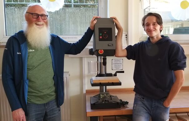 Werner Überdick von der Schornsteinfeger-Glückstour und Damian freuen sich über die neue Tischbohrmaschine.