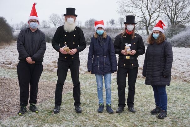 Marvin, Marie und Jolien von der Schülerfirma "Die Zauberer" übergeben ein kleines Geschenk an Werner Überdiek und Olaf Meiner von Glückstour.