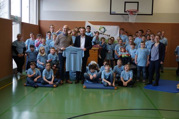 Bernd Müller von Teamwork Höxter GmbH und David Peine von der VerbundVolksbank freuen sich, die Schul-T-Shirts übergeben zu können.