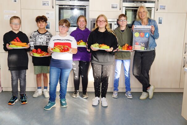 Die Lernenden freuen sich gemeinsam mit Frau Rohde von der Schulentwicklungskonferenz  Nachhaltigkeit über das frische Obst und Gemüse.